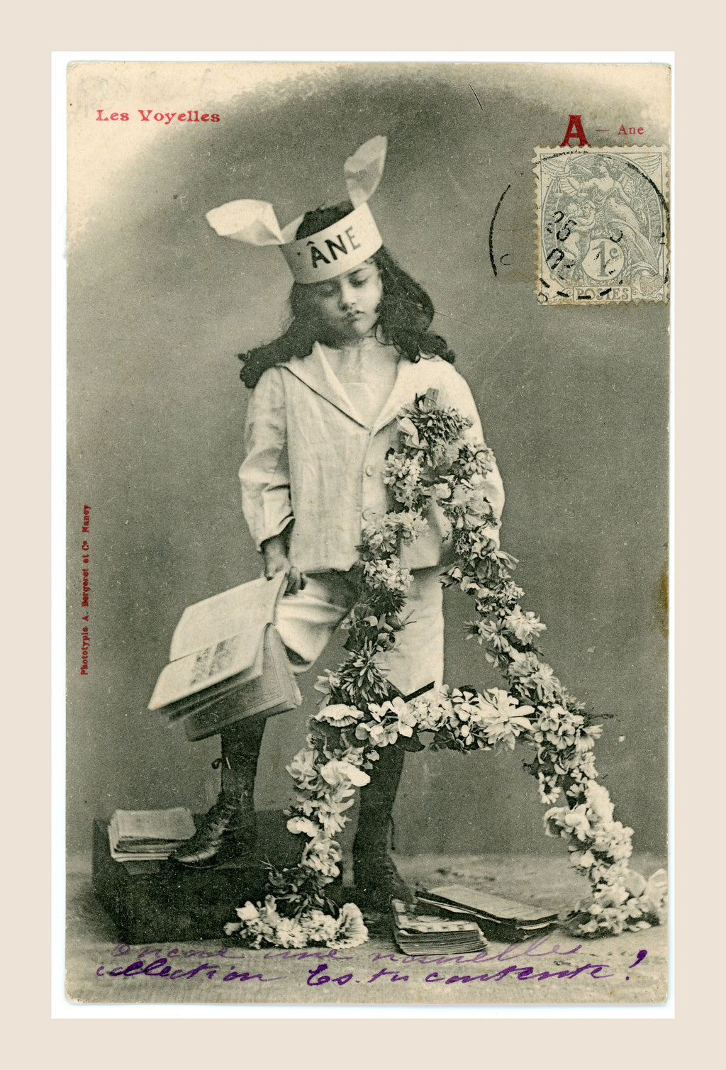 Antique French Bergeret postcard Les Voyelles, letter A for Âne, showing a young girl in a donkey-ear bonnet with books and floral decoration, circa 1905.