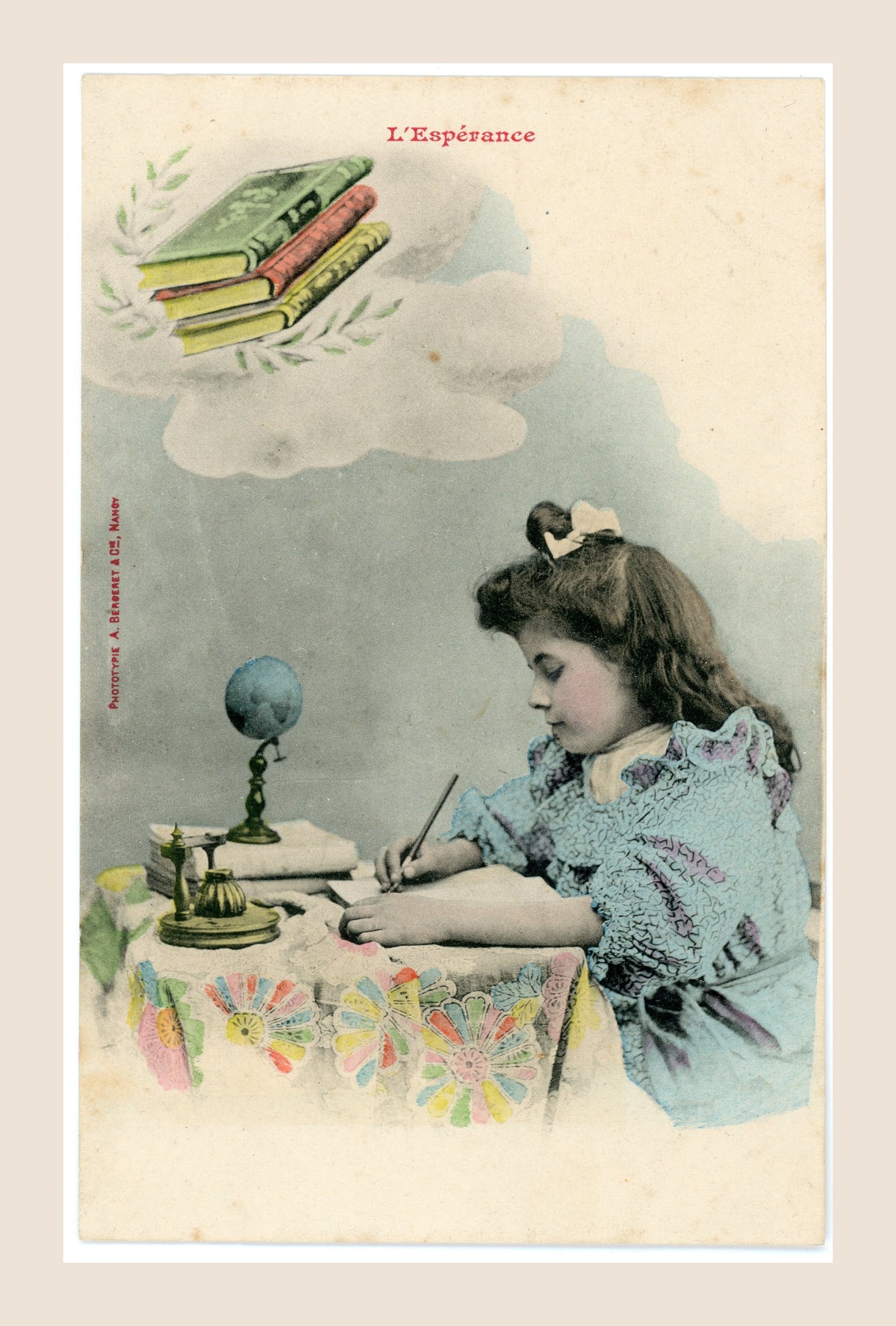 Antique French colorized Bergeret postcard L’Espérance, Hope, showing a young girl writing at a desk with books, globe and inkwell, Belle Époque circa 1905.