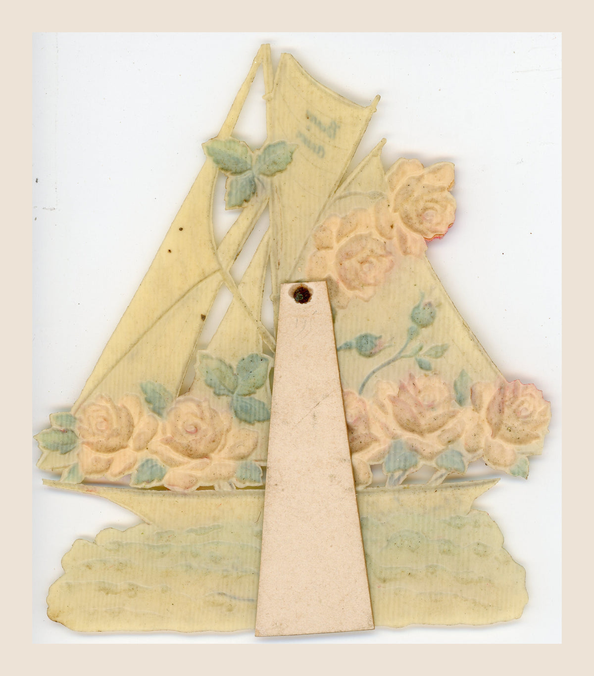 Reverse of an antique sailboat-shaped greeting card showing the raised floral design, a central display support and age-related yellowing and spots.
