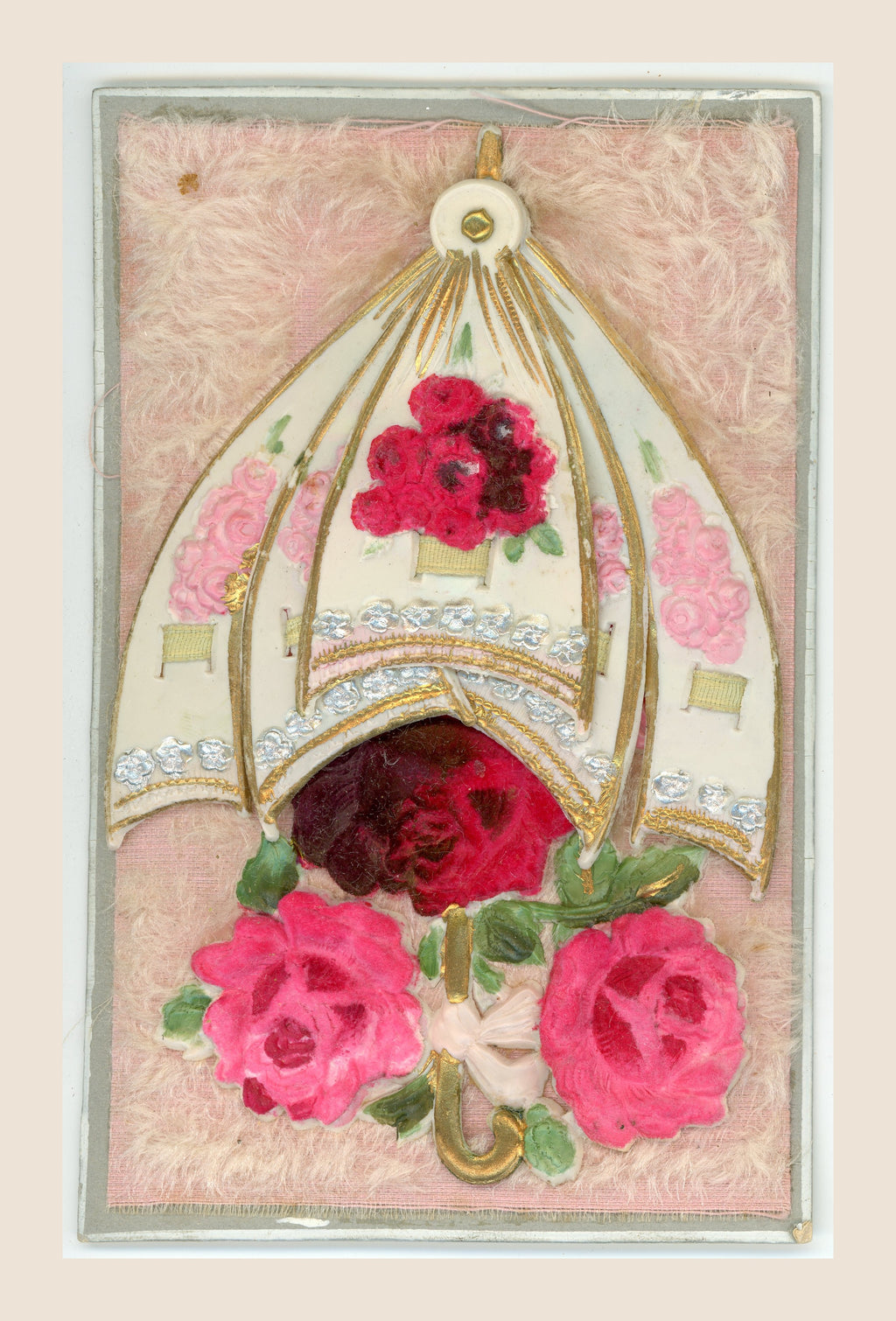 Antique postcard showing the overlapping panels of a movable floral parasol drawn together above pink and red fabric roses on a pink textile background.