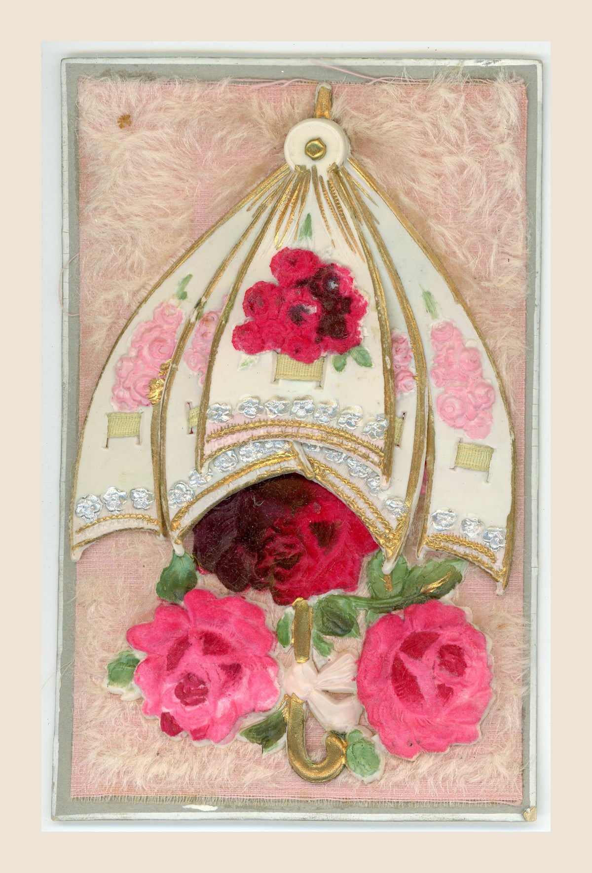 Antique postcard showing the overlapping panels of a movable floral parasol drawn together above pink and red fabric roses on a pink textile background.