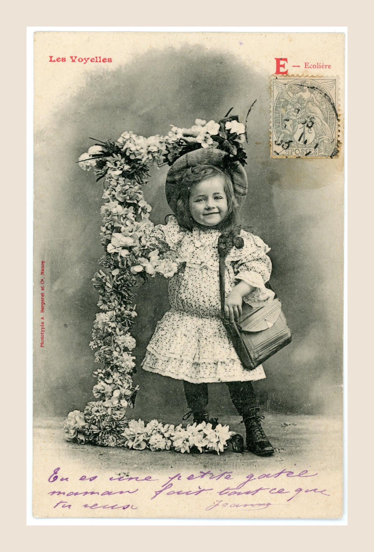 Antique Bergeret Les Voyelles postcard, letter E for Écolière, showing a smiling Belle Époque schoolgirl with satchel beside a floral letter E.