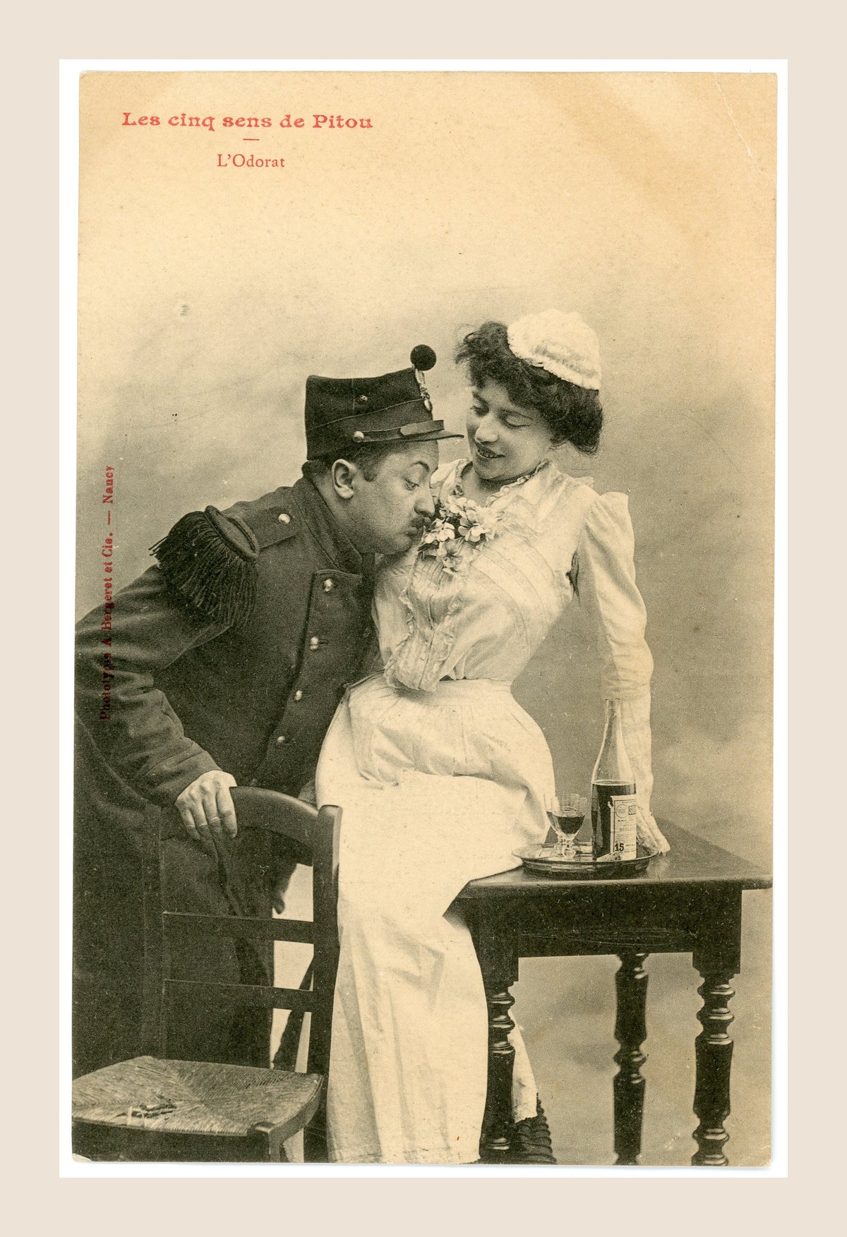 Antique Bergeret postcard L'Odorat, depicting a French soldier smelling flowers held by a smiling woman, humorous Belle Époque photography.