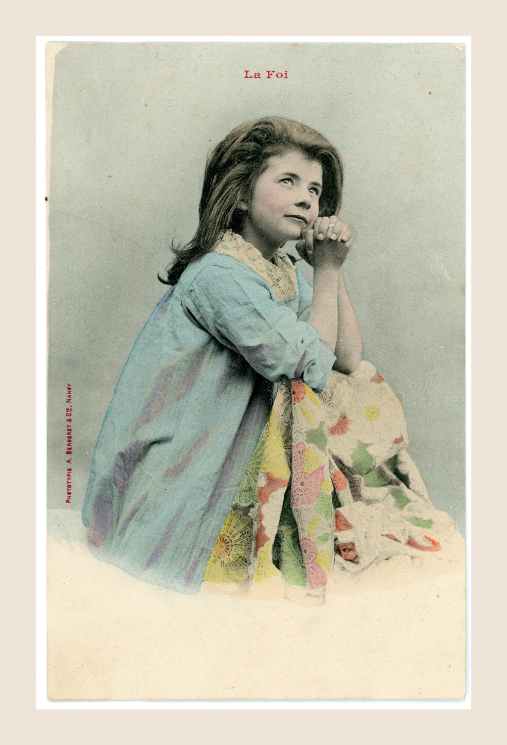 Antique colorized French Bergeret postcard La Foi, Faith, depicting a young girl with clasped hands in prayer, wearing a blue dress, Belle Époque circa 1905.
