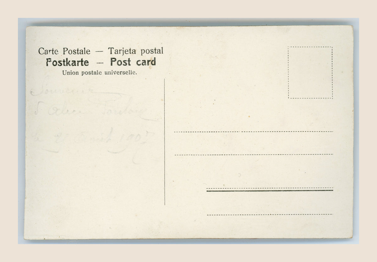 Reverse of an antique postcard with multilingual postal headings, faint pencil writing, a blank stamp box and scattered age-related spots.