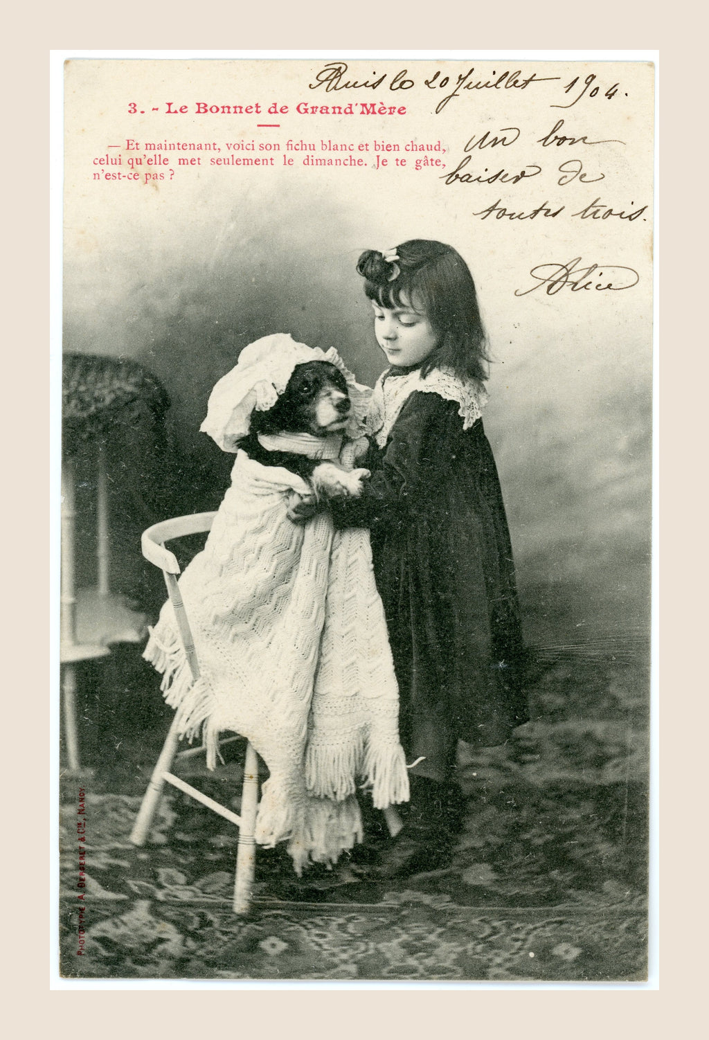 Albert Bergeret Grandmother's Bonnet postcard number 3 showing a Belle Époque girl wrapping her dog Médor in a large white shawl and bonnet.