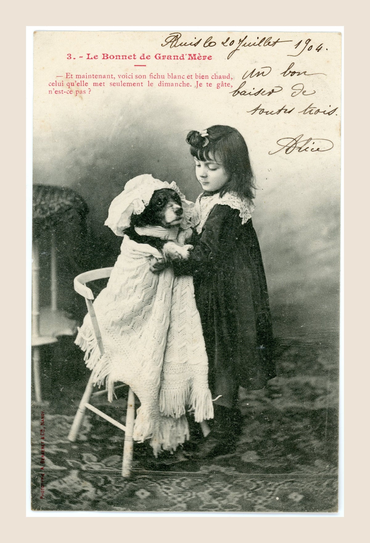 Albert Bergeret Grandmother's Bonnet postcard number 3 showing a Belle Époque girl wrapping her dog Médor in a large white shawl and bonnet.