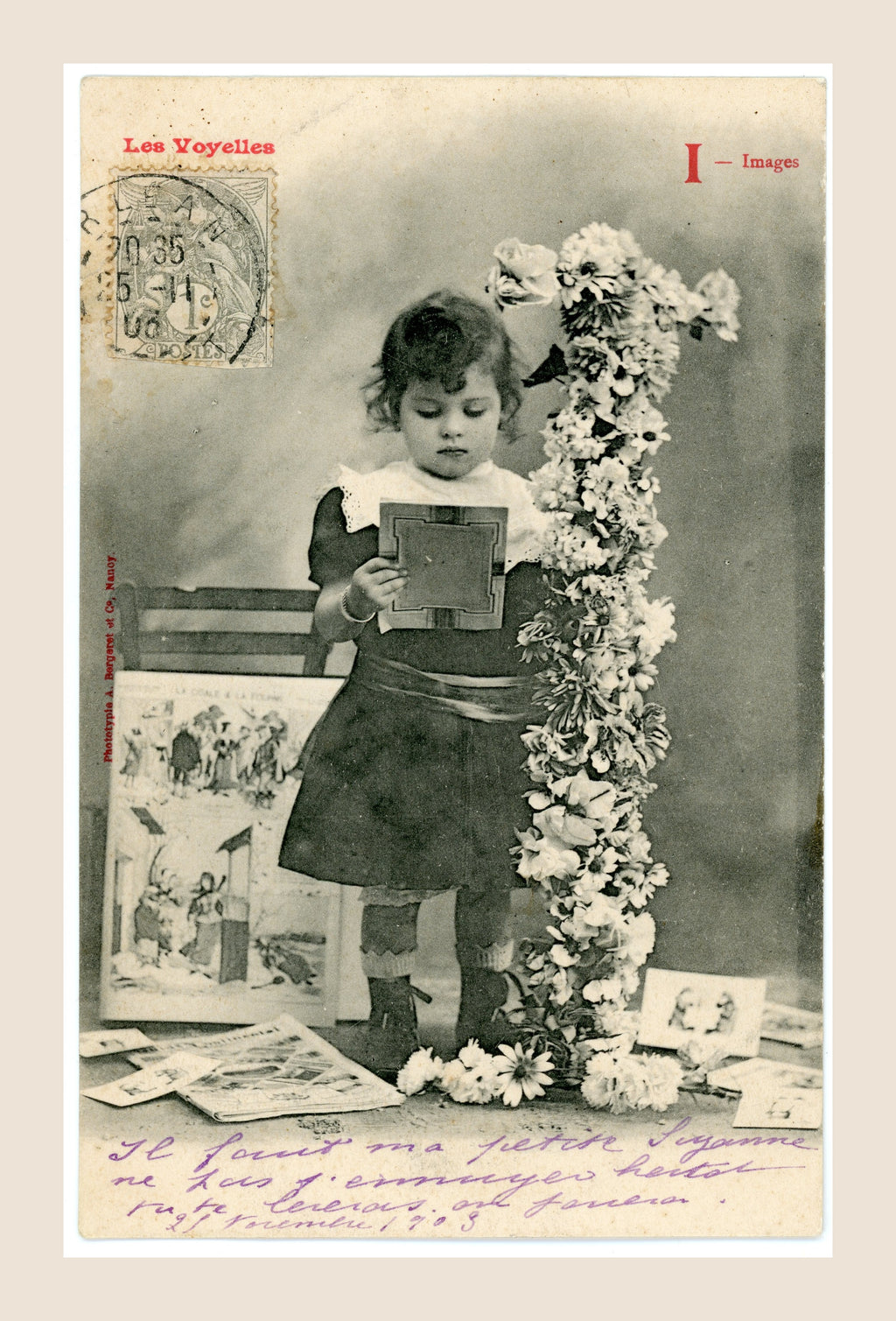 Antique French Bergeret postcard, letter I for Images, featuring a little girl looking at picture cards beside a flower-covered letter I, early 1900s.