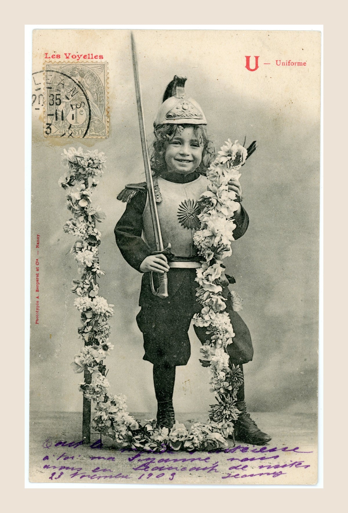 Antique Bergeret Les Voyelles postcard, letter U for Uniforme, depicting a smiling girl in theatrical military costume holding a sword beside floral decorations.