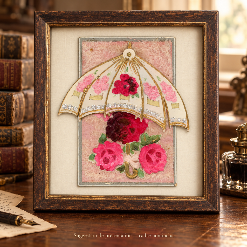 Antique postcard with a movable cream parasol spread open above pink and red fabric roses on pink textile, displayed in a patinated wooden frame on a vintage desk. Frame not included.