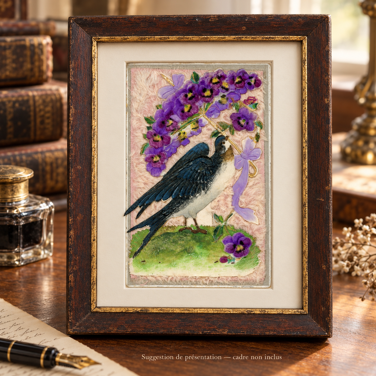 Antique postcard featuring a swallow beneath a purple pansy parasol on pale pink textile, displayed in a patinated wooden frame on a vintage writing desk. Frame not included.
