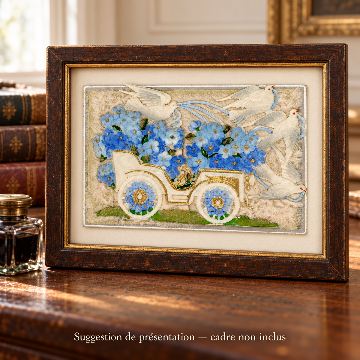 Antique postcard with a cream motor car, blue fabric flowers and four white doves in relief, displayed in a dark wooden frame on a vintage writing desk. Frame not included.