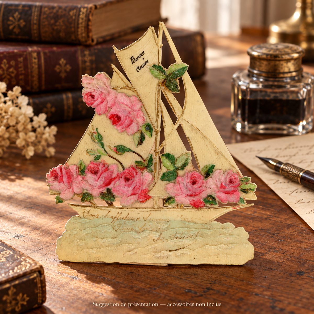 Antique sailboat-shaped Bonne Année greeting card with pink roses in relief and a handwritten dedication, standing on a vintage writing desk. Accessories not included.