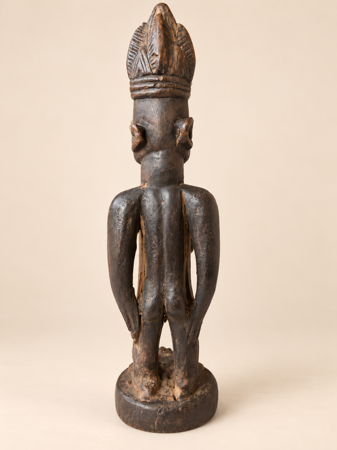 Rear view of Yoruba female Ere Ibeji wooden figure without cowrie cloak, showing carved back, arms and aged patina