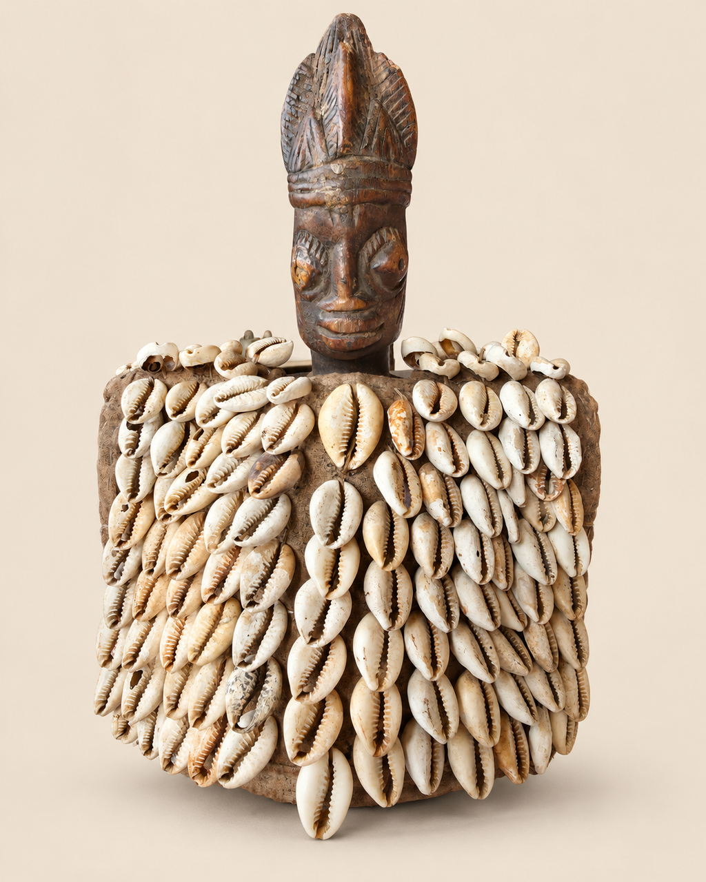 Front view of Yoruba female Ere Ibeji figure with antique textile cloak covered in cowrie shells