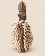 Side view of Yoruba Ibeji figure showing aged textile cloak, stitching and natural cowrie shells