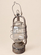 Rear three-quarter view of a vintage Panzer lantern, showing the protective wire cage, wick adjustment wheel and reservoir seam.