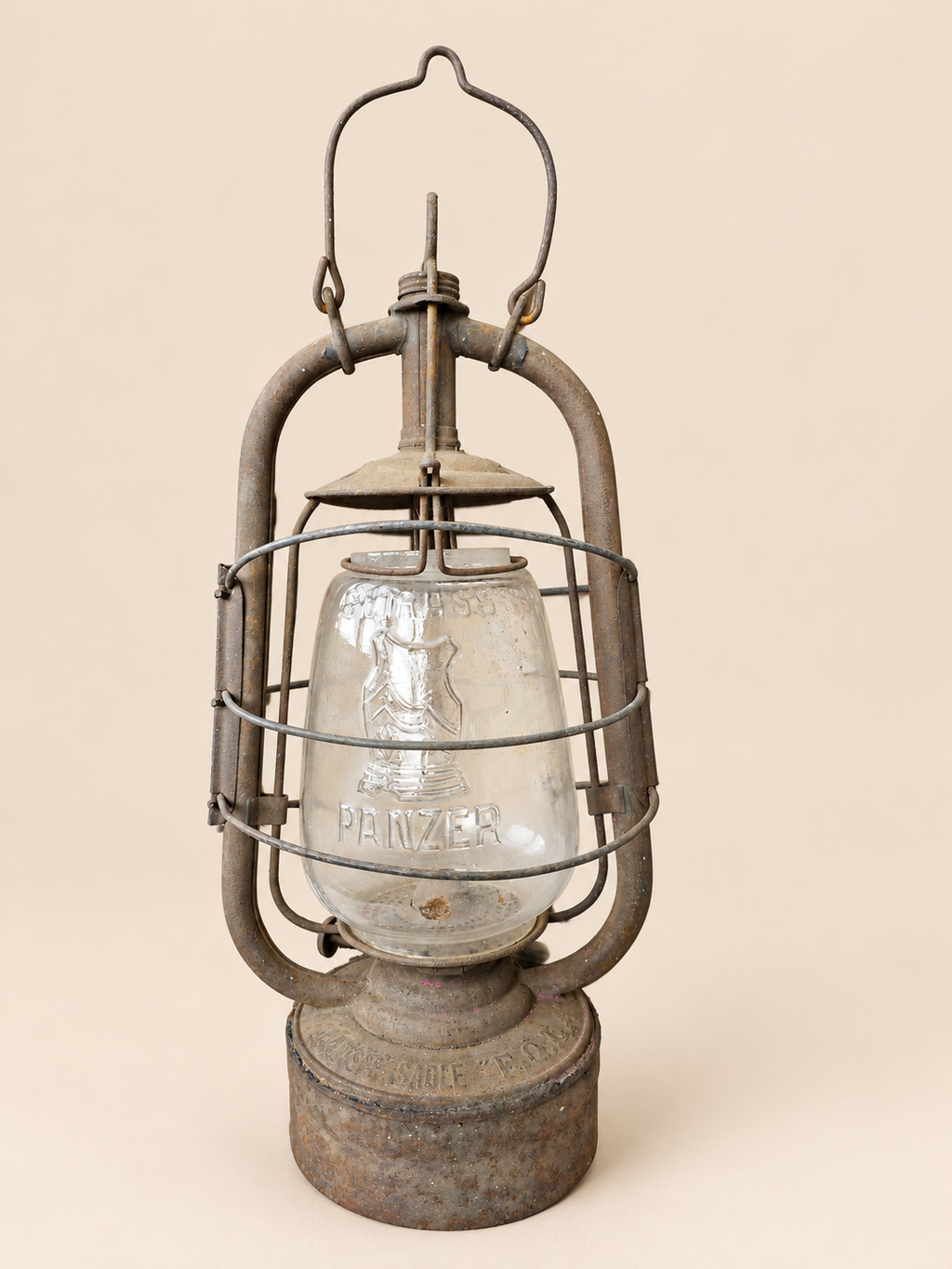 Front view of a vintage Panzer Cuirass hurricane lantern with raised handle, embossed glass globe and aged metal frame.