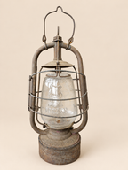 Front view of a vintage Panzer Cuirass hurricane lantern with raised handle, embossed glass globe and aged metal frame.