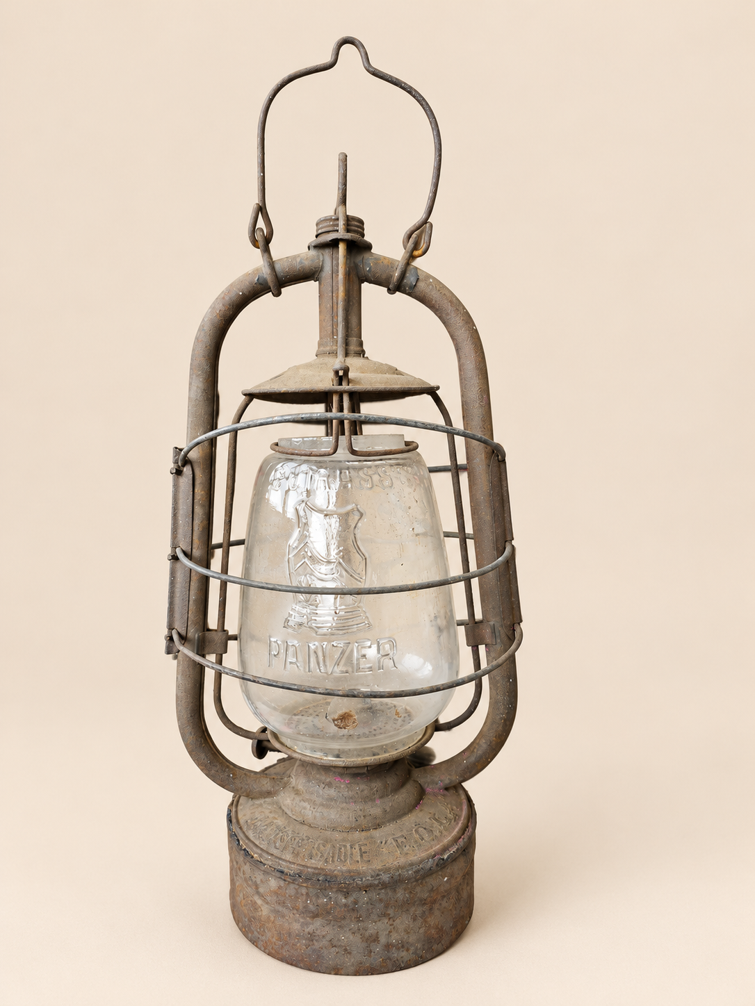 Front view of a vintage Panzer Cuirass hurricane lantern with raised handle, embossed glass globe and aged metal frame.