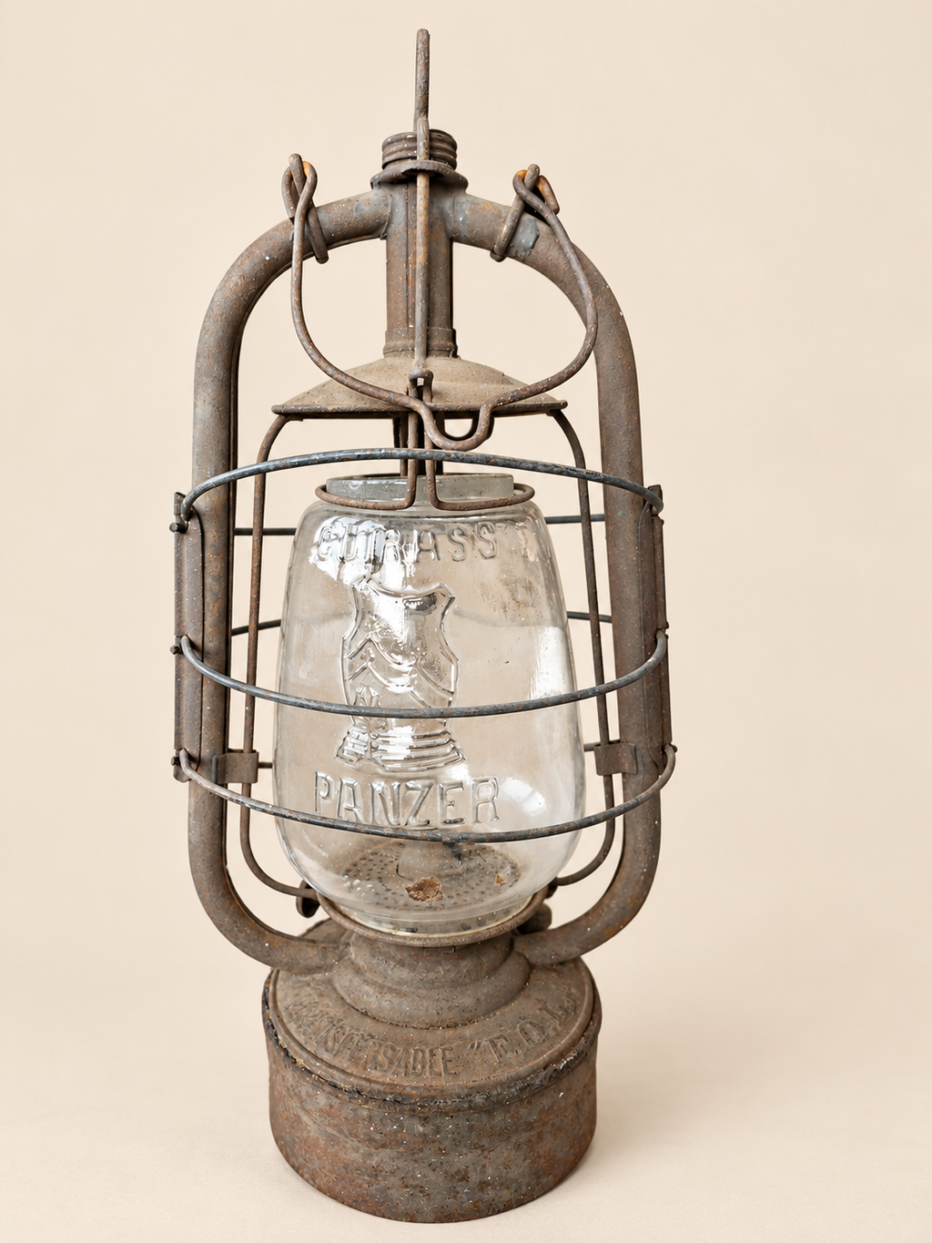 Front view of a vintage Panzer Cuirass lantern with its carrying handle folded down, showing the embossed glass and metal frame.