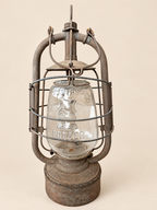 Front view of a vintage Panzer Cuirass lantern with its carrying handle folded down, showing the embossed glass and metal frame.