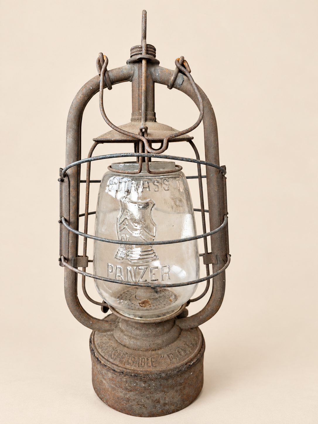 Front view of a vintage Panzer Cuirass lantern with its carrying handle folded down, showing the embossed glass and metal frame.