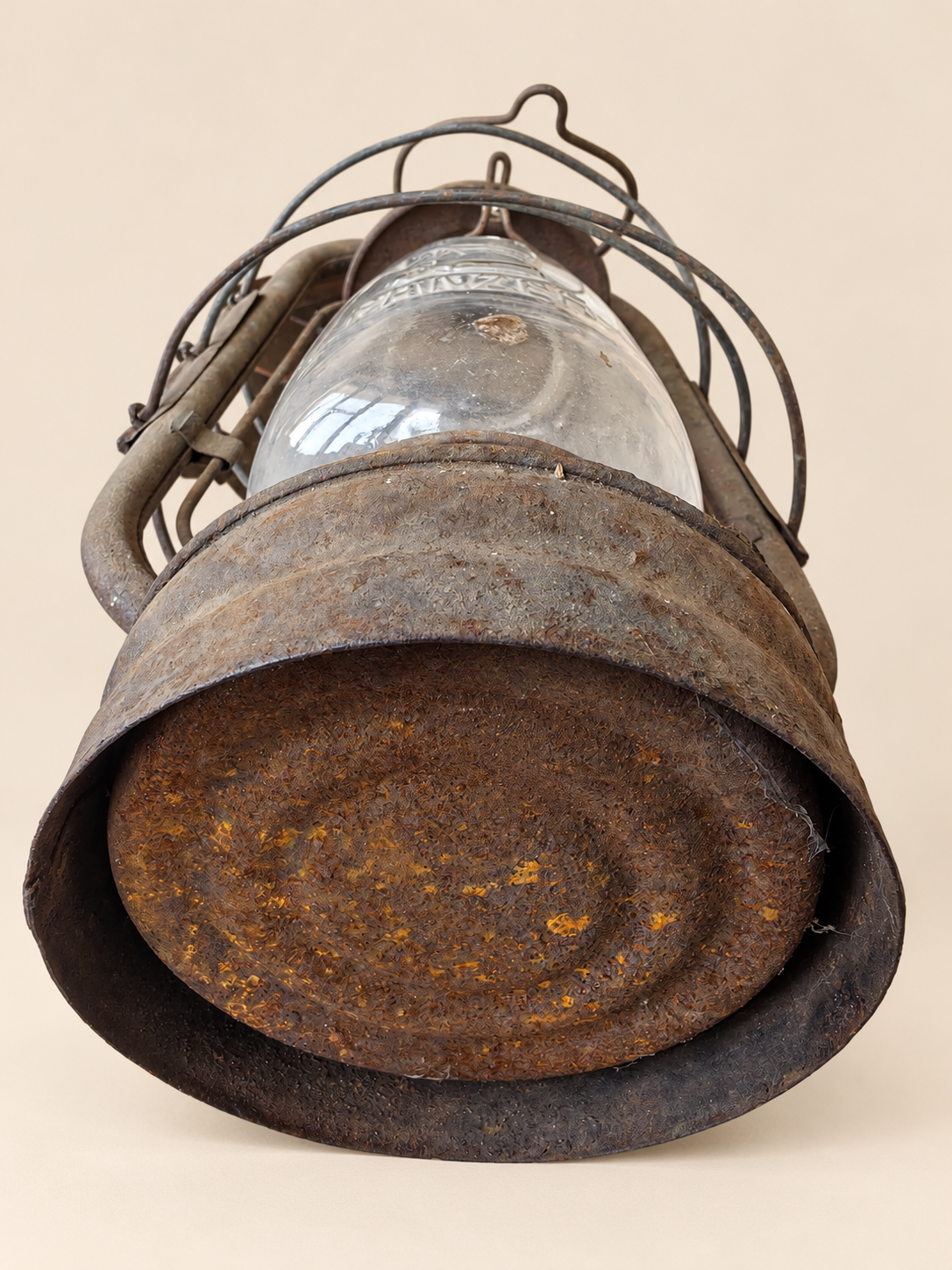Underside of a vintage Panzer lantern lying on its side, showing rust and oxidation across the circular metal base.