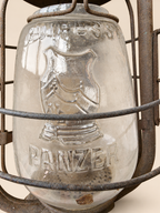 Close-up of the lantern’s glass globe with embossed Cuirass Panzer lettering and armour emblem behind weathered protective wires.