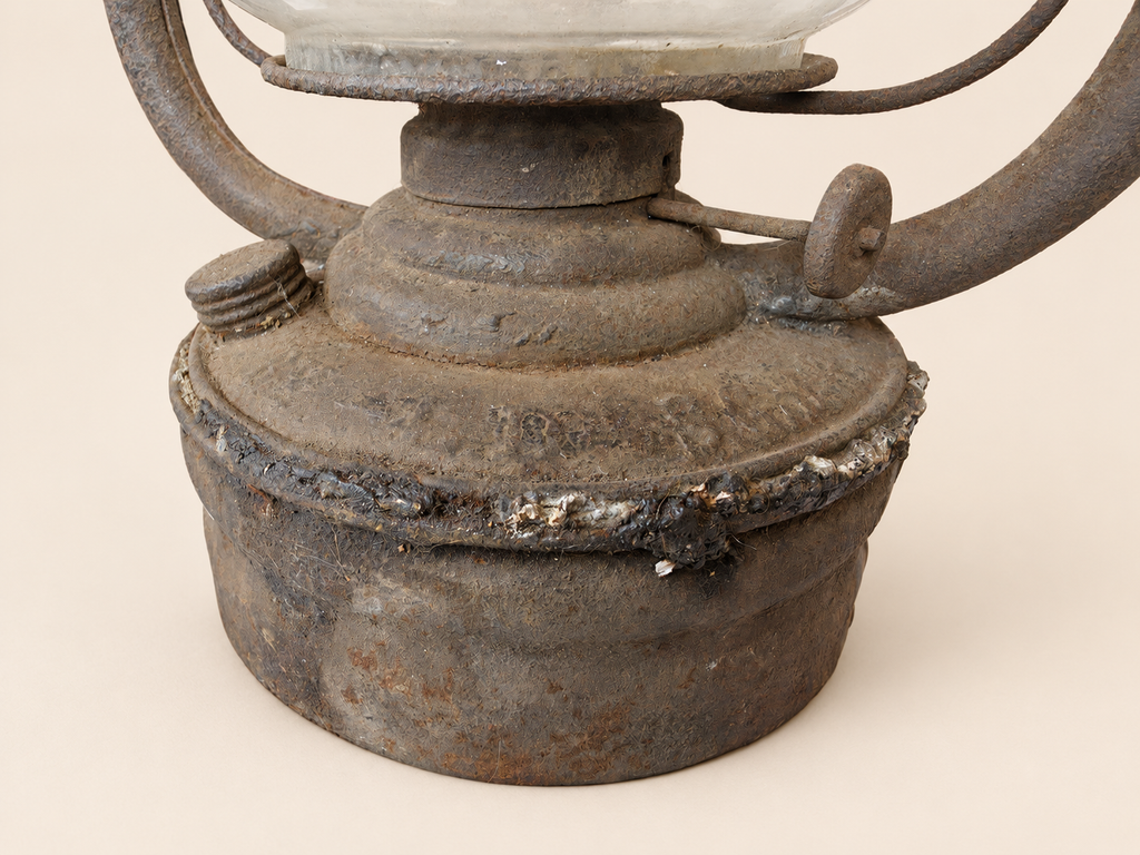 Close-up of the Panzer lantern’s rusted metal reservoir, showing an irregular solder seam, filler cap and wick adjustment wheel.