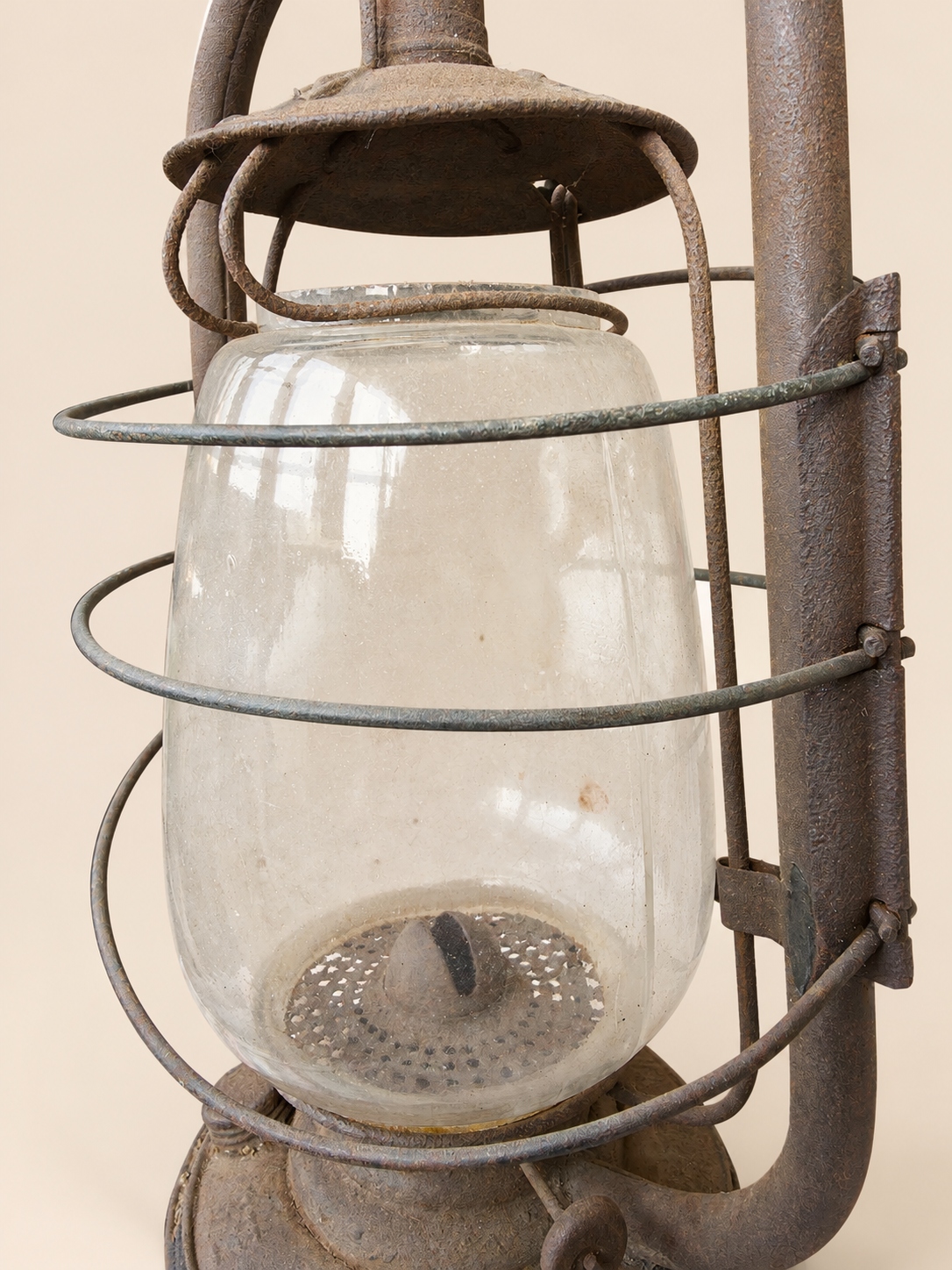 Rear close-up of the Panzer lantern’s glass globe, showing the wick, perforated burner plate and surrounding metal wire cage.